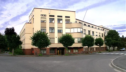 En stor bygning med trær foran seg